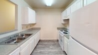 Located at 1890 Cathedral Mills Ln. in Rock Hill, South Carolina, this single-floor residence offers a well-organized layout designed for comfortable everyday living. The galley-style kitchen is efficiently arranged with white cabinetry lining both walls, granite-style countertops, a stainless steel sink, and white appliances including a range and refrigerator, all set above durable wood-look flooring. Adjacent to the kitchen, the dining area is accented by an elegant chandelier and flows seamlessly into the main living space, which features the same wood-look flooring, a ceiling fan, and glass-paneled doors that invite natural light and provide outdoor access. The bedrooms are finished with soft wall-to-wall carpeting and include windows fitted with blinds that frame views of the surrounding community. The bathroom is clean and functional, outfitted with a white vanity cabinet topped with a granite-style countertop, a single sink, a lighted mirror, and a full tub-shower combination. Throughout the residence, neutral tones, textured ceilings, and consistent finishes create a cohesive and practical living environment suited for a wide range of lifestyles.