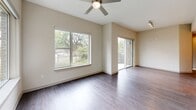 Located at 1115 Town Creek Drive in Austin, TX, this well-appointed two-bedroom, one-bathroom residence offers a thoughtfully designed single-level layout with modern finishes throughout. The open-concept living area is bathed in natural light from large windows that frame views of mature trees, and a ceiling fan adds comfort to the bright, airy space. A sliding glass door leads to a private balcony framed by exposed brick, extending the living area outdoors. Dark hardwood-style flooring flows through the main living spaces, providing a warm contrast to the neutral wall tones.

The kitchen is a standout feature, showcasing a large center island with a white quartz countertop and undermount sink, two-tone cabinetry in white and grey, stainless steel appliances, track lighting, and elegant glass pendant fixtures. The seamless connection between the kitchen and living area makes the layout ideal for both daily living and entertaining.

The spacious primary bedroom offers generous proportions, a tray ceiling detail, and a ceiling fan, while the second bedroom features hardwood-style flooring and a window with outdoor views. The bathroom is finished with large-format tile, a soaking tub with shower, a vanity with built-in shelving, and clean, modern fixtures. An in-unit laundry area with a full-size washer completes this practical and stylish home.