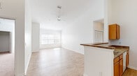 This well-designed single-story home offers three bedrooms, two bathrooms, and four closets across a thoughtfully laid-out floor plan. The open-concept living and kitchen area serves as the heart of the home, featuring soaring vaulted ceilings, light hardwood-style flooring, and a ceiling fan that enhances the airy feel. Large windows flood the living room with natural light, creating a bright and welcoming atmosphere. The kitchen is equipped with warm wood cabinetry, dark granite-style countertops, a breakfast bar peninsula, and white appliances including a range and full-size refrigerator, with a pantry closet conveniently nearby. The primary bedroom is generously sized with hardwood-style flooring, large windows, and direct access to a spacious walk-in closet fitted with wire shelving. Additional bedrooms feature plush carpet, natural light from exterior windows, and closet storage. The bathrooms are finished with granite-style countertops and include a tub-shower combination. Consistent white walls and trim throughout the home lend a clean, neutral aesthetic, while the mix of hardwood-style flooring in main areas and carpet in bedrooms adds comfort and practicality. A central hallway connects all rooms efficiently, completing this functional and well-lit home.