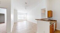 This well-designed single-story home offers three bedrooms, two bathrooms, and four closets across a thoughtfully laid-out floor plan. The open-concept living and kitchen area serves as the heart of the home, featuring soaring vaulted ceilings, light hardwood-style flooring, and a ceiling fan that enhances the airy feel. Large windows flood the living room with natural light, creating a bright and welcoming atmosphere. The kitchen is equipped with warm wood cabinetry, dark granite-style countertops, a breakfast bar peninsula, and white appliances including a range and full-size refrigerator, with a pantry closet conveniently nearby. The primary bedroom is generously sized with hardwood-style flooring, large windows, and direct access to a spacious walk-in closet fitted with wire shelving. Additional bedrooms feature plush carpet, natural light from exterior windows, and closet storage. The bathrooms are finished with granite-style countertops and include a tub-shower combination. Consistent white walls and trim throughout the home lend a clean, neutral aesthetic, while the mix of hardwood-style flooring in main areas and carpet in bedrooms adds comfort and practicality. A central hallway connects all rooms efficiently, completing this functional and well-lit home.