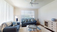 This single-story residence offers a thoughtfully arranged floor plan with distinct living, dining, and sleeping areas. The living room serves as the heart of the home, featuring crown molding, hardwood-style flooring, a ceiling fan, and large windows with plantation shutters that invite generous natural light. A neutral color palette and open sightlines contribute to an airy, comfortable atmosphere.

Adjacent to the living room, the dining area accommodates a round table and seating for four, with hardwood-style flooring continuing underfoot and a decorative ledge adding architectural interest. The kitchen features warm wood cabinetry, dark countertops, a peninsula breakfast bar with seating potential, and track lighting overhead. A window above the counter brings in additional daylight.

Both bedrooms are comfortably scaled, each with carpet flooring, ceiling fans, and windows with blinds providing natural light and privacy. The primary bathroom includes an extended vanity with granite-style countertops, warm wood cabinetry, tile flooring, and access to a walk-in closet. The second bathroom mirrors this layout, offering a tiled tub-shower combination, a vanity with matching countertops, and an adjacent walk-in closet.