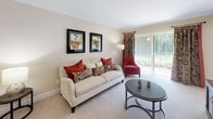 This single-floor residence offers a thoughtfully designed layout that balances comfort and practicality. The living room serves as the heart of the home, featuring neutral carpeting, crown molding, and a large sliding glass door that floods the space with natural light while providing direct access to an outdoor area with greenery views.

The kitchen is efficiently arranged with warm oak cabinetry, dark granite-style countertops, tile flooring, and white appliances including a range, microwave, refrigerator, and sink. It opens conveniently to a dedicated dining area. A separate utility closet within the kitchen area houses a stacked washer and dryer, adding significant convenience.

The bedrooms are carpeted and generously proportioned, each equipped with ceiling fans for year-round comfort. One bedroom features a spacious reach-in closet with bifold doors and direct access to a bathroom, while another offers ample room for a full bedroom suite and a dedicated workspace.

The bathroom includes a full soaking tub and shower combination enclosed by white subway tile, chrome fixtures, and a decorative curtain. Throughout the residence, a consistent neutral color palette and clean finishes create a cohesive, welcoming ambiance.