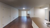Located at 2865 W Elliot Dr, Unit D106, in Spokane, WA, this single-floor unit offers a practical and comfortable layout designed for everyday living. The open-concept living and dining area features rich, dark hardwood-style flooring that adds warmth and visual depth to the space. A sliding glass door with vertical blinds allows natural light to fill the room, while a wall-mounted HVAC unit ensures year-round comfort. The kitchen is efficiently designed with dark cabinetry, black appliances including a refrigerator, electric range, and microwave, complemented by a peninsula countertop that provides additional workspace and a natural division between the kitchen and living area. Track lighting overhead keeps the space well-lit and functional. The bedrooms are finished with plush carpeting and neutral wall tones, creating a calm and restful atmosphere. Each bedroom features a ceiling fan with light fixture and closet access with built-in shelving, offering practical storage solutions. The layout flows cohesively throughout, with clean white walls, consistent trim work, and thoughtful transitions between living and private spaces. Overall, the unit presents a clean, move-in ready environment suited for comfortable residential living in Spokane.