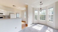Located at 247 Marcliffe Dr in Valparaiso, Indiana, this well-appointed home offers a thoughtfully designed layout spread across multiple levels, connected by carpeted stairs with a warm wood handrail. The main living area is bright and open, anchored by a classic fireplace framed by large windows that invite generous natural light and outdoor views. Adjacent to the living room is a sun-drenched dining area featuring a distinctive bay window configuration and an elegant pendant light fixture, creating an inviting space for everyday meals or entertaining. The kitchen is functional and clean, outfitted with white cabinetry, a tile backsplash, gas range, built-in microwave, and a full-size refrigerator. A glass-panel door provides direct access to the outdoors. The bedrooms are carpeted and well-sized, each featuring ample closet space, ceiling fans, and windows that allow natural light to fill the rooms. One room includes a door leading to an outdoor area, adding a convenient exterior connection. Additional rooms throughout the home feature hardwood flooring and large windows with tree-lined views. The home's neutral color palette and consistent finishes create a cohesive, move-in-ready atmosphere throughout.