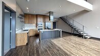 Located at 201 S Gibson Rd in Henderson, NV, this modern two-story residence offers 2,330 square feet of thoughtfully designed living space, with 3 bedrooms, 3 bathrooms, and 2 closets. The main floor (1,210 sq ft) features an open-concept kitchen and living area anchored by a sleek kitchen island with a gas cooktop and stainless steel hood vent. Warm wood cabinetry, a tile backsplash, double wall ovens, and durable wood-look vinyl flooring lend the space a contemporary aesthetic. A striking open-riser staircase with cable railing connects the floors. The upper level (1,120 sq ft) is carpeted throughout and includes all three bedrooms. The primary bedroom spans 170 square feet and is highlighted by expansive floor-to-ceiling windows offering sweeping panoramic views of the Henderson valley and distant mountains. Additional bedrooms include dedicated closets with built-in shelving. Bathrooms feature large-format gray tile surrounds with soaking tubs. A hallway with wood-look flooring connects the upper living spaces. Recessed lighting, dark trim accents, and abundant natural light throughout contribute to the home's clean, modern character.