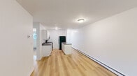 Located at 50 Rinaldi Blvd in Poughkeepsie, NY, this two-bedroom, one-bathroom unit offers a practical and well-appointed single-floor layout. The combined kitchen and living area forms the heart of the space, featuring light wood flooring that runs throughout and crisp white walls that lend a clean, bright atmosphere. The kitchen is equipped with white cabinetry, dark countertops, stainless steel appliances including a range and refrigerator, a double-basin sink, and a peninsula that provides additional prep and storage space. Baseboard heating runs along the perimeter, ensuring warmth throughout. The primary bedroom offers generous proportions, a wall-mounted air conditioning unit, and a sliding glass door that opens to an outdoor area with greenery views. The second bedroom includes a built-in closet with bifold doors and shares the same warm wood flooring. One bedroom also features a painted brick accent wall, adding a subtle textural detail. The full bathroom is finished with gray tile flooring and a full tub and shower surround. A hallway connects the rooms efficiently, completing this functional and neatly presented layout.