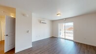 Located at 230 Battelle Boulevard in Richland, Washington, this modern single-floor unit offers a thoughtfully designed open-concept layout finished with consistent wood-style luxury vinyl flooring throughout the main living areas. The spacious living room is equipped with a wall-mounted ductless mini-split HVAC unit for efficient climate control and features a sliding glass door that opens to a private patio, filling the room with natural light and providing outdoor access and views of the surrounding neighborhood. Adjacent to the living area, the dining space is illuminated by a pendant light fixture and flows directly into the galley-style kitchen. The kitchen is outfitted with light wood-tone cabinetry, white countertops, and a full suite of stainless steel appliances, including a refrigerator, electric range, over-the-range microwave, and dishwasher. The bedroom features plush wall-to-wall carpeting and multiple windows that allow ample natural light. The bathroom includes a vanity with light wood cabinetry, a toilet, and wood-style flooring. In-unit laundry facilities are also present, adding further convenience to this well-appointed, move-in-ready space.