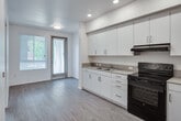 Located at 2222 E First St in Santa Ana, California, this single-floor unit offers a clean, contemporary design with functional layouts and modern finishes throughout. The kitchen is a standout feature, equipped with white shaker-style cabinetry extending to the upper walls for generous storage, neutral-toned countertops, a double stainless steel sink, a black electric range with overhead ventilation, and a full-size refrigerator. Recessed lighting illuminates the space, while durable wood-look flooring runs throughout the main living and kitchen areas, adding warmth and easy maintenance. The open connection between the kitchen and living area creates a practical, flowing layout. Natural light enters through a windowed entry door fitted with blinds, brightening the main living space. The bedroom features soft carpeting underfoot and a large window with blinds that allows for ample natural light and outdoor views. The bathroom is well-appointed with a full soaking tub and tiled shower surround, a single-sink vanity with matching cabinetry, built-in open shelving for storage, a wall mirror, and wood-look flooring that ties the space together cohesively. The unit's neutral color palette and modern hardware selections give the interior a fresh, move-in-ready feel.