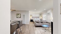 Located at 887 Saint Charles Drive in Thousand Oaks, California, this single-floor studio offers a well-organized and efficiently designed layout. The open-plan main area seamlessly integrates the living, dining, and sleeping zones, finished with light wood-style flooring and a neutral white palette that creates a bright, clean ambiance throughout. Recessed lighting illuminates the space, complemented by large windows that invite ample natural light and offer views of mature trees and the surrounding greenery outside.

The living area features a comfortable seating arrangement centered around a low coffee table, with wall-mounted TV storage adding to the functional design. A dedicated dining nook accommodates a round table with seating for several guests and includes a ceiling fan overhead. The galley-style kitchen is outfitted with white shaker cabinetry, dark countertops, subway tile backsplash, and a full suite of stainless steel appliances including a gas range, refrigerator, and built-in microwave.

Two closets provide practical storage, while a dedicated laundry area adds everyday convenience. The bathroom maintains the same clean aesthetic with wood-look tile flooring and white cabinetry. A hallway connects the functional spaces, and a welcoming entrance completes this efficiently planned, move-in-ready studio.