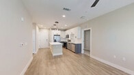 Located in Sanford, FL, this well-appointed 2-bedroom, 3-bathroom residence offers a thoughtfully designed single-floor layout with generous living space. The open-concept kitchen and living area serves as the heart of the home, showcasing a large center island with quartz countertops, crisp white upper cabinetry, contrasting grey lower cabinets, and a full suite of stainless steel appliances. Statement pendant lighting adds a modern touch above the island, while light wood-look flooring extends throughout the main living areas. The bedrooms are carpeted for comfort, each featuring ceiling fans and windows with blinds that invite natural light. The primary bedroom is notably spacious and includes a dedicated walk-in closet with wire shelving systems for ample storage. The bathrooms are finished to a high standard, with one featuring a double-sink vanity with grey cabinetry, a bold-framed mirror, and a glass-enclosed shower adorned with elegant marble-look tile. Two dedicated closets provide additional storage throughout the residence. The overall aesthetic is clean and contemporary, with neutral tones, modern fixtures, and quality finishes creating a bright, cohesive ambiance throughout.