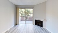 This thoughtfully designed 2-bedroom, 2-bathroom residence offers a clean, modern aesthetic throughout its efficiently utilized single-floor layout. The open living room serves as the heart of the home, featuring light gray luxury vinyl plank flooring, a textured ceiling, and a classic fireplace as a focal point. A full-width sliding glass door opens to a private balcony overlooking lush, mature trees, flooding the space with natural light and providing a serene outdoor retreat.

The galley-style kitchen is outfitted with white shaker cabinetry, sleek white countertops, a mosaic tile backsplash, and stainless steel appliances including a gas range, refrigerator, and dishwasher — offering both style and functionality in a compact footprint.

The primary bedroom is a comfortable and well-proportioned retreat with a large window framing greenery views and the same consistent vinyl plank flooring found throughout. The second bedroom similarly benefits from natural light and tree-lined sightlines. A connecting hallway links the bedrooms to the two full bathrooms, each finished with white vanities, framed mirrors, tub-shower combinations, and clean, neutral tones. The overall ambiance is bright, fresh, and move-in ready.