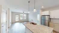 Located at 2410 Smith Gln Rd in Charlotte, NC, this well-designed 2-bedroom, 2-bathroom single-story home offers a thoughtfully laid-out floor plan with contemporary finishes throughout. Light hardwood-style flooring flows seamlessly from room to room, creating a cohesive and airy feel across the entire home.

The open-concept kitchen and living area serves as the heart of the space. The kitchen is appointed with crisp white shaker cabinetry, granite countertops, a herringbone tile backsplash, and a full suite of stainless steel appliances. A center island with a built-in sink and pendant lighting adds both functionality and style, while recessed ceiling lights illuminate the space.

The living room is bright and welcoming, featuring large windows with natural light and a ceiling fan. Both bedrooms continue the light flooring and neutral palette, each equipped with ceiling fans and windows overlooking the surrounding neighborhood. The primary bedroom offers a generous layout with access to a walk-in closet featuring multi-tier wire shelving systems for ample storage.

Both bathrooms are finished with granite-topped vanities and full tub-shower combinations with built-in shelving, complemented by wood-look flooring and clean white surrounds. A second walk-in closet provides additional storage convenience throughout the home.