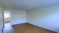 This two-story space offers a clean, straightforward layout spread across two floors, providing ample room for a variety of uses. The interior is characterized by its neutral, light-toned walls that create a bright and airy atmosphere throughout. Smooth, white ceilings complement the understated color palette, lending a sense of openness to each room.

The flooring is a warm hardwood-style material in a rich, medium-brown tone, adding a touch of warmth and continuity to the living areas. Clean white baseboards provide a crisp finish at the floor line, contributing to the overall tidy and well-maintained aesthetic of the space.

The rooms are generously proportioned, offering flexible, open areas that can accommodate a range of furniture arrangements and purposes. The minimalist design approach keeps the focus on functionality and adaptability. Natural light appears to filter into the space, further enhancing the welcoming and comfortable ambiance.

Overall, this two-floor property presents a practical and well-kept interior with a neutral design foundation, making it an ideal canvas for personalization. Its consistent finishes and thoughtful layout provide a solid and versatile foundation suitable for a wide range of occupants and uses.