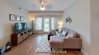 This thoughtfully designed 2-bedroom, 2-bathroom single-floor residence offers a comfortable and functional layout with quality finishes throughout. The open-concept living area features hardwood-style flooring, a ceiling fan, and French doors that invite natural light while providing access to an outdoor space. The kitchen is outfitted with rich dark cabinetry, granite countertops, black appliances including a refrigerator, electric range, and built-in microwave, and a peninsula with pendant lighting that connects seamlessly to the dining area. The dining space accommodates a round table beneath an elegant chandelier, with a window providing additional natural light. The primary bedroom is carpeted and includes a ceiling fan, generous windows, and direct access to a full bathroom featuring a soaking tub, a dark vanity with a wide countertop, and tile flooring. The second bedroom also features plush carpet and access to a walk-in closet, with an adjacent full bathroom offering a dark vanity and tile flooring. A dedicated in-unit laundry closet houses a full-size top-loading washer and dryer. Neutral gray tones and consistent finishes throughout create a cohesive and welcoming ambiance.