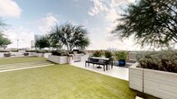 This distinctive single-floor space blends sophisticated interior design with impressive outdoor living. Inside, the dining area serves as a focal point, anchored by a striking round green marble table with an ornate pedestal base, surrounded by rattan-style chairs atop a woven area rug. Polished concrete floors run throughout, lending an industrial-modern character to the interior. White walls provide a clean backdrop for curated wall art, while a sliding barn door adds architectural charm and serves as a thoughtful design detail connecting interior spaces. Recessed lighting and track lighting ensure the interior is well-illuminated throughout.

The crowning feature of this space is the expansive rooftop terrace, which offers sweeping views of a city skyline. The terrace is thoughtfully designed with a combination of artificial turf and a paved entertaining area, creating distinct zones for relaxation and dining. Large white planter boxes filled with mature trees and lush shrubs provide privacy and a garden-like atmosphere. A built-in outdoor kitchen with a gas grill makes the terrace ideal for entertaining, while outdoor dining furniture offers a comfortable setting to take in the panoramic urban views. The overall ambiance is modern, curated, and effortlessly connected to the outdoors.