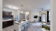 Located at 4917 Martin Luther King Blvd in Houston, TX, this well-appointed two-bedroom, two-bathroom residence offers a functional and modern single-floor layout. The open-concept kitchen and living area serves as the heart of the home, featuring dark espresso cabinetry, a striking blue mosaic tile backsplash, stainless steel appliances, and a large white island with bar seating — ideal for both meal prep and casual dining. Pendant and track lighting illuminate the kitchen, while light wood-style flooring flows throughout the space. The living room is bright and welcoming, with a ceiling fan, large windows, and a glass door providing direct access to an outdoor patio area. Both bedrooms are comfortably proportioned, each equipped with a ceiling fan, natural light from windows with blinds, and dedicated closet space. The primary bedroom offers a cozy, private feel with ample room for a full bed and additional furnishings. The two bathrooms are finished with clean white subway tile surrounds and full bathtub-shower combinations. Throughout the residence, neutral wall tones and consistent flooring create a cohesive, move-in-ready aesthetic suited for everyday living.