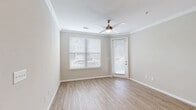Located at Ashley Gardens in Charleston, SC, this well-appointed one-bedroom, one-bathroom residence offers a thoughtfully designed single-floor layout with a clean, modern aesthetic throughout. The combined kitchen and living area serves as the heart of the home, featuring light wood-style flooring, crown molding, and a ceiling fan with ample natural light streaming through large windows with blinds and a glass-panel door. The kitchen is equipped with stainless steel appliances, including a refrigerator, electric range, and microwave, complemented by granite-style countertops, a peninsula with a built-in sink, pendant lighting, and two-tone gray cabinetry with track lighting overhead. The living area flows seamlessly from the kitchen, offering a bright and open feel. The bedroom is carpeted for comfort, features a ceiling fan, and is illuminated by a natural-light window. A spacious walk-in closet with wire shelving provides generous storage. The bathroom includes a full soaking tub and shower combination with white tile surround, wood-style flooring, and granite-accented vanity. Neutral warm-gray walls unify the space, creating a calm and cohesive ambiance throughout.