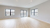 Located at 150 S 15th St in Clear Lake, Iowa, this thoughtfully designed three-story home offers four bedrooms and three bathrooms across a well-distributed layout. The ground level features a spacious garage with a concrete floor and freshly drywalled walls, providing direct interior access to the home. The main floor serves as the heart of the residence, combining the kitchen and living room in an open-concept arrangement, complemented by a convenient half bath with a pedestal sink, warm-toned wood-look flooring, and natural light through black-framed windows. A staircase connects each level with a clean, modern aesthetic throughout. The upper floor houses the bedrooms, including a generously sized primary suite with an angled ceiling detail, a walk-in closet equipped with wire shelving and a small window, and an en suite bathroom. Additional bedrooms on this level share well-appointed bathrooms featuring tile flooring and dark-cabinetry vanities. Throughout the home, light wood-look flooring, soft gray walls, recessed lighting, and crisp white trim create a cohesive, contemporary feel. Multiple windows frame views of the surrounding tree line, filling the interior with natural light and a sense of openness.
