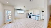 Located at 1540 NW 30th St in Oklahoma City, this modern two-story residence offers a clean, contemporary design spread across two floors. Light wood-style flooring runs consistently throughout the home, contributing to a bright and cohesive aesthetic.

The main floor hosts a spacious open-concept living and kitchen area. The kitchen is well-appointed with white shaker-style cabinetry, dark countertops, and a full suite of stainless steel appliances including a refrigerator, range, microwave, and dishwasher. A horizontal picture window brings in natural light, while exposed ductwork adds an industrial accent. A glass-panel exterior door on the main level provides additional natural light and outdoor access.

The upper floor contains both bedrooms and the full bathroom. The generously sized primary bedroom features a ceiling fan and a large black-framed window overlooking the surrounding neighborhood. The second bedroom is equally bright, with its own window offering open sky views. The shared bathroom is thoughtfully finished with a grey vanity, white quartz countertop, a modern rectangular mirror, and matte black fixtures. Light-toned stairs connect the two levels, maintaining the home's clean, minimalist character throughout.