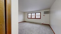 Located at 520 S Church St in Decatur, Illinois, this single-floor unit presents a straightforward, functional layout across several well-defined rooms. Consistent design elements—including warm wood trim framing multi-pane windows and rich red-toned baseboards—unify the interior throughout.

The main living area is generously proportioned, featuring plush grey carpeting, a baseboard heating system, and a wall-mounted air conditioning unit. Large, multi-pane windows with wood surrounds allow natural light to fill the space. Additional rooms, likely serving as bedrooms, mirror this aesthetic with grey carpeting, ceiling fans with light fixtures, baseboard heating, and windows offering outdoor views of surrounding structures.

The kitchen is equipped with warm wood cabinetry, light granite-style countertops, a double-basin stainless steel sink, and white appliances including an electric range and refrigerator. Tile flooring and a natural wood door add practicality and warmth to the space.

The bathroom features a modern vanity with a light stone countertop, a wood-framed mirror, tile flooring, and neutral walls, presenting a clean and functional design.

Overall, the unit maintains a neutral, move-in-ready aesthetic with practical climate control features and consistent warm wood accents throughout.