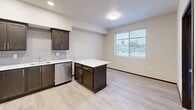 Located in Tumwater, WA, this well-appointed one-bedroom, one-bathroom unit offers a thoughtfully designed layout across a single floor. The open-concept kitchen and living area serves as the heart of the home, featuring dark espresso cabinetry with brushed hardware, a gray subway tile backsplash, stainless steel appliances including a refrigerator, range, microwave, and dishwasher, and a central island with a crisp white countertop — ideal for both meal prep and casual dining. Light wood-look luxury vinyl flooring flows throughout the main living areas, enhancing the bright, airy atmosphere. A large window in the living area admits generous natural light and offers views of the surrounding neighborhood. The spacious bedroom is finished with plush carpet and features its own large window, two closets including a walk-in, and direct access to a dedicated laundry area with a stacked Whirlpool washer and dryer. A versatile den provides additional flexible living space, also carpeted with a bright window. The full bathroom is clean and functional, with a dark vanity, large mirror, and a tub/shower combo with light vinyl flooring. Two closets and a hallway complete this efficient and modern floor plan.