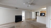 Located at 201 Kingstowne Rd in Newport News, Virginia, this single-floor, 2-bedroom, 2-bathroom home offers a well-organized layout with functional living spaces throughout. The living room serves as the heart of the home, highlighted by a classic black fireplace, a ceiling fan, and vaulted ceilings with a striking arched window that floods the room with natural light. Large windows along two walls further enhance the bright, open atmosphere, and carpet flooring adds warmth underfoot. The kitchen is efficiently designed with light wood cabinetry, dark granite-style countertops, black appliances including a range, dishwasher, and refrigerator, and a peninsula breakfast bar that connects to the living area. A stacked washer and dryer unit is conveniently located just off the kitchen. Both bedrooms are carpeted and well-proportioned, with the primary bedroom offering ample closet space. Three closets total are distributed throughout the home. The two bathrooms are clean and functional, each featuring a tub-shower combination, with one showcasing wood-look flooring and a white vanity with integrated sink. The home also includes a dedicated laundry area, making daily living convenient and comfortable.