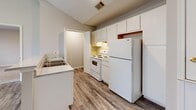 This two-bedroom, two-bathroom unit at Carraway Commons in Jonesboro, Arkansas, offers a practical and efficiently organized single-floor layout. The kitchen serves as a central feature, equipped with white cabinetry extending to the ceiling for ample storage, a white electric range, a full-size refrigerator, and a stainless steel sink. A peninsula with a light granite-style countertop separates the kitchen from the adjacent living area, creating an open, connected feel. Wood-look vinyl flooring runs throughout the kitchen and bathrooms, lending a clean, cohesive aesthetic.

Both bedrooms are carpeted and finished in neutral tones, with windows that admit natural light. The primary bedroom is a comfortable size and features direct access to one of the two bathrooms, providing added convenience. The second bedroom also benefits from natural light through a window and is served by the second full bathroom. Both bathrooms are finished with white fixtures, including tub-shower combinations and overhead cabinetry for storage.

The unit includes two dedicated closets and a connecting hallway that organizes the flow between rooms. The overall palette of neutral beige walls, white trim, and consistent flooring choices gives the space a clean, move-in ready appearance throughout.