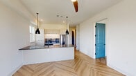 Located at 212 Melba St in Dallas, TX, this well-designed 2-bedroom, 2-bathroom residence offers a thoughtfully laid-out single floor. The open-concept living, dining, and kitchen area serves as the heart of the home, anchored by a sleek white kitchen island with a dark concrete-style countertop and an undermount sink. White flat-front cabinetry, stainless steel appliances, a built-in wine cooler, and industrial-style black pendant lighting complete the modern aesthetic. Herringbone-patterned hardwood floors flow seamlessly throughout the space, adding warmth and visual interest. A striking teal accent door adds a bold pop of color to the main living area. Both bedrooms are bright and airy, benefiting from natural light through large windows, with one offering expansive views of the Dallas skyline and surrounding neighborhood. Each bedroom is complemented by its own bathroom; one bath features floor-to-ceiling slate-toned tile in the walk-in shower with a glass enclosure, while both bathrooms are appointed with illuminated round mirrors and marble-topped vanities with matte black fixtures. Additional highlights include four closets — one of which is a spacious walk-in with built-in shelving and double hanging rods — a dedicated laundry area, a hallway, and a private balcony.