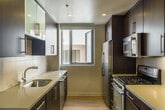 Located at 1418 Fifth Street in Santa Monica, California, this single-story unit offers a well-designed layout with a cohesive modern aesthetic throughout. The living areas feature light wood flooring that contributes to a bright, open atmosphere, while recessed and track lighting provide functional illumination across the space.

The kitchen is outfitted in a galley configuration with dark espresso cabinetry contrasted by light quartz countertops. Stainless steel appliances—including a gas range, refrigerator, microwave, and dishwasher—are complemented by glass-front upper cabinets and a window that draws in natural light. The clean lines and efficient layout make it a highly functional space.

The bedrooms are carpeted for comfort and include windows that allow natural light to filter in. At least one bedroom features a built-in closet with frosted glass sliding doors and integrated shelving and hanging rods, offering practical storage solutions.

The bathrooms are finished with light ceramic tile flooring and include dark-toned vanity cabinetry with light countertops and a large mirror. One bathroom features a tub and shower combination enclosed by a sliding glass door, while another includes accessibility grab bars. Both are clean and contemporary in design, maintaining a consistent palette with the rest of the unit.