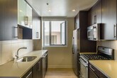 Located at 1418 Fifth Street in Santa Monica, California, this single-story unit offers a well-designed layout with a cohesive modern aesthetic throughout. The living areas feature light wood flooring that contributes to a bright, open atmosphere, while recessed and track lighting provide functional illumination across the space.

The kitchen is outfitted in a galley configuration with dark espresso cabinetry contrasted by light quartz countertops. Stainless steel appliances—including a gas range, refrigerator, microwave, and dishwasher—are complemented by glass-front upper cabinets and a window that draws in natural light. The clean lines and efficient layout make it a highly functional space.

The bedrooms are carpeted for comfort and include windows that allow natural light to filter in. At least one bedroom features a built-in closet with frosted glass sliding doors and integrated shelving and hanging rods, offering practical storage solutions.

The bathrooms are finished with light ceramic tile flooring and include dark-toned vanity cabinetry with light countertops and a large mirror. One bathroom features a tub and shower combination enclosed by a sliding glass door, while another includes accessibility grab bars. Both are clean and contemporary in design, maintaining a consistent palette with the rest of the unit.