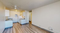 Located at 32 Montebello Rd in Pueblo, Colorado, this single-floor unit offers a practical and efficiently designed layout suited for comfortable everyday living. The open-concept living and kitchen area is finished with wood-look laminate flooring throughout, providing a clean and cohesive aesthetic. A ceiling fan with integrated lighting keeps the space well-ventilated and illuminated.

The kitchen is equipped with white cabinetry, an electric coil range, a full-size refrigerator, and a range hood, all set against neutral countertops. The galley-style configuration maximizes the available space while keeping essentials within easy reach. An electrical panel is conveniently accessible within the kitchen area.

The living area is bright and open, featuring a window fitted with a wall-mounted air conditioning unit, allowing for natural light while maintaining climate control. Baseboard heating provides warmth during cooler months. The textured ceiling adds a classic touch consistent throughout the unit.

The bathroom is neatly appointed with a single-vanity with cabinet storage, a mirrored medicine cabinet, overhead lighting, a toilet, and a walk-in shower, all finished with the same wood-look flooring for continuity. The overall design of the space prioritizes functionality and ease of maintenance.