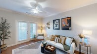 Located at Fairway Village Way in Whitsett, NC, this single-story residence offers a thoughtfully designed layout that maximizes comfort and functionality. The open-concept living, dining, and kitchen area serves as the heart of the home, anchored by warm hardwood-style flooring and elegant crown molding throughout. The kitchen is outfitted with rich dark cabinetry, granite countertops, stainless steel appliances including a refrigerator, microwave, and range, and a breakfast bar that provides additional seating and workspace. The living room is bright and inviting, featuring a ceiling fan, crown molding, and French doors that open to a private patio, allowing natural light to pour in. The spacious bedroom offers a ceiling fan, a large window with natural light, and a generous walk-in closet with built-in shelving. The bathroom features a dark wood vanity with a wide mirror, white countertops, and tile flooring. Additional practical spaces include a pantry, laundry room, utility room, and multiple closets for ample storage. The overall ambiance is clean, modern, and welcoming throughout.