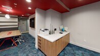 Located at 635 Robinson Ave in San Diego's Hillcrest district, this single-floor commercial space makes a strong design statement through its consistent use of bold color and contemporary finishes. The signature red-painted ceilings contrast sharply with crisp white walls throughout, creating a dynamic and energetic atmosphere reinforced by recessed lighting and rich teal-toned patterned carpeting underfoot.

The reception area serves as the central hub of the space, featuring a wood-cabinet workstation topped with a clean white surface and outfitted with office equipment, décor, and built-in technology. A wall-mounted display adds functionality to the welcoming entry point.

A dedicated conference room offers a large wood-surface table with integrated red power and connectivity ports at its center, surrounded by upholstered seating. The room is lined with layered dark acoustic panels that run horizontally along the walls, enhancing both sound quality and visual texture. A sculptural pendant light fixture adds an artistic focal point overhead.

A private lounge or consultation room provides a more intimate setting, furnished with two plush turquoise swivel chairs accented by deep purple throw pillows, small side tables, and decorative wall-mounted panels that contribute to acoustic performance and aesthetic interest.

Sleek glass-panel doors with black frames allow visual connectivity between zones while maintaining separation. The overall design is cohesive, modern, and purpose-built for a professional yet creative environment.