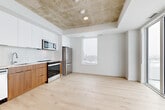 Located at 300 Mìwàte Pvt in Ottawa, this modern 2-bedroom, 2-bathroom unit offers a thoughtfully designed layout with contemporary finishes throughout. The open-concept living and kitchen area is anchored by striking exposed concrete ceilings that contrast beautifully with crisp white walls and light hardwood flooring. The kitchen is equipped with stainless steel appliances, including a built-in microwave, electric range, and full-size refrigerator, complemented by two-tone cabinetry featuring white upper cabinets and warm wood lower drawers. Floor-to-ceiling sliding glass doors flood the living area with natural light and provide direct access to a private balcony, framing sweeping city views. A second window further brightens the space, reinforcing an airy, open ambiance. The bedrooms are serene and minimalist, with light hardwood floors continuing throughout and balcony access from the primary bedroom. A clean hallway connects the rooms with matte black hardware accents on doors adding a modern touch. The two bathrooms are finished with large-format neutral tiles, walk-in showers with glass surrounds, and warm wood vanities topped with white counters, maintaining the unit's cohesive, contemporary aesthetic.