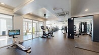 Located at 18220 N 68th St in Phoenix, AZ, this state-of-the-art fitness center spans a generously sized single floor, offering a comprehensive and well-organized workout environment. The space is divided into distinct training zones, each thoughtfully equipped to support a wide range of fitness activities.

The cardio zone features a lineup of modern treadmills, ellipticals, and stationary cycling bikes, all positioned along floor-to-ceiling glass walls and sliding doors that flood the area with natural light and offer views of the surrounding palm-lined exterior. The strength training area is outfitted with a full rack of dumbbells, multiple weight benches, power racks, and cable machines, complemented by large mirrors that enhance the sense of space.

A dedicated functional training zone includes a turf lane, a heavy punching bag, kettlebells, medicine balls, battle ropes, and suspension equipment, all set against motivational wall graphics that energize the atmosphere. Additional specialized equipment includes sled push platforms and interactive fitness machines.

Throughout the facility, durable rubber flooring provides safety and comfort, while recessed and tray ceiling lighting ensures excellent visibility. The open, airy layout, modern dark accent columns, and climate-controlled environment make this fitness center a premium destination for all levels of training.