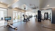 Located at 18220 N 68th St in Phoenix, AZ, this state-of-the-art fitness center spans a generously sized single floor, offering a comprehensive and well-organized workout environment. The space is divided into distinct training zones, each thoughtfully equipped to support a wide range of fitness activities.

The cardio zone features a lineup of modern treadmills, ellipticals, and stationary cycling bikes, all positioned along floor-to-ceiling glass walls and sliding doors that flood the area with natural light and offer views of the surrounding palm-lined exterior. The strength training area is outfitted with a full rack of dumbbells, multiple weight benches, power racks, and cable machines, complemented by large mirrors that enhance the sense of space.

A dedicated functional training zone includes a turf lane, a heavy punching bag, kettlebells, medicine balls, battle ropes, and suspension equipment, all set against motivational wall graphics that energize the atmosphere. Additional specialized equipment includes sled push platforms and interactive fitness machines.

Throughout the facility, durable rubber flooring provides safety and comfort, while recessed and tray ceiling lighting ensures excellent visibility. The open, airy layout, modern dark accent columns, and climate-controlled environment make this fitness center a premium destination for all levels of training.