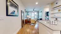 This well-appointed single-floor residence offers a cohesive open-concept design with warm hardwood flooring extending seamlessly throughout every room. The living area is bright and inviting, centered around large windows with plantation shutters that allow generous natural light to fill the space. A ceiling fan adds both function and style, while curated wall art and thoughtfully arranged furnishings contribute to a modern, welcoming ambiance.

The kitchen is a standout feature, equipped with stainless steel appliances including a gas range, microwave, and refrigerator. Crisp white cabinetry, a classic subway tile backsplash, and a quartz-topped island with bar seating make it both functional and visually appealing — ideal for cooking and casual dining alike.

The bedrooms are calm and comfortable retreats. The primary bedroom features a bold accent wall, a large window with abundant natural light, and ample space for furnishings. Additional bedrooms maintain the same clean, neutral palette with natural light.

The bathroom offers a refined vanity with white cabinetry, quartz countertops, and matte black hardware, maintaining the consistent modern aesthetic found throughout the space. Built-in shelving provides additional storage and display options. Overall, the residence presents a polished, contemporary living environment with thoughtful design details at every turn.