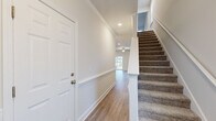 Located in Statesboro, Georgia, this two-story home offers a thoughtfully designed layout across two floors, providing comfortable and functional living spaces. The main floor features a welcoming entryway with crisp white paneled doors, crown molding, and hardwood-style flooring that flows throughout. The open-concept kitchen is a standout, equipped with white shaker cabinetry, a classic subway tile backsplash, quartz countertops, a central island, and a full suite of stainless steel appliances including a French door refrigerator, range, microwave, and dishwasher. The living room is bright and airy, featuring a ceiling fan, sliding glass doors that open to the outdoors, and multiple windows that invite abundant natural light and outdoor views. Upstairs, the spacious primary bedroom includes a ceiling fan, ample natural light from well-placed windows, and access to a generously sized en-suite bathroom with dual white vanities, brushed nickel hardware, and warm hardwood-style flooring. The second bedroom is equally well-appointed. Throughout the home, a neutral color palette, clean architectural lines, and quality finishes create a cohesive, modern aesthetic that is both functional and inviting.