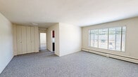 Located at 3400 Terrace Dr in Alexandria, Virginia, this single-floor unit offers three bedrooms, one full bathroom, and a dedicated laundry room. The layout is practical and straightforward, with neutral cream-toned walls and grey carpet throughout the living and sleeping areas, creating a clean, cohesive look.

The spacious primary bedroom is notably generous in size, featuring built-in closets with bi-fold doors and direct access to an additional walk-in closet, providing ample storage. The two secondary bedrooms are each carpeted and equipped with windows fitted with blinds, allowing natural light while maintaining privacy. Baseboard heating units run along the walls in multiple rooms.

The kitchen is outfitted with dark wood upper cabinetry, a white gas range with four burners, and overhead cabinetry for additional storage. The full bathroom features classic pink wall tiles accented with a navy tile border, a full-size soaking tub, chrome fixtures, and a frosted window that brings in diffused natural light.

The living area is open and well-lit, anchored by a large picture window with views of the surrounding neighborhood and mature trees. The unit also includes a dedicated laundry room, adding everyday convenience to this functional Alexandria residence.