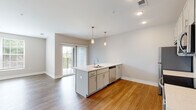 Located at 65 S. Washington Ave in Columbus, OH, this single-floor residence offers a thoughtfully designed open-concept layout filled with natural light. The kitchen serves as the heart of the space, showcasing a large center island with a built-in sink, crisp white quartz countertops, soft gray cabinetry, and a full suite of stainless steel appliances including a refrigerator, electric range, microwave, and dishwasher. Elegant pendant lighting hangs above the island, adding a modern touch. Warm hardwood-style flooring flows throughout the main living areas, complementing the neutral wall tones and clean architectural lines. The living area is bright and open, with large windows and sliding glass door access to a private balcony with outdoor views. Bedrooms are carpeted for comfort and feature generous windows that bring in natural light. The primary bedroom includes a spacious walk-in closet equipped with dual-level wire shelving for ample storage. The bathroom is well-appointed with hardwood-style flooring, a tiled soaking tub and shower combination, a vanity with under-sink cabinetry, and a framed mirror. The overall ambiance is clean, contemporary, and move-in ready.