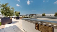Located in the heart of Los Angeles at 8377 Blackburn Ave, this rooftop terrace offers a thoughtfully designed outdoor retreat with sweeping panoramic views of the city skyline, surrounding hills, and beyond. The space is organized into several distinct zones, each tailored for a different outdoor experience.

The terrace features large-format porcelain tile and warm wood-toned deck flooring throughout, providing a clean, contemporary aesthetic. Landscaping is a central design element, with generously sized raised planters filled with drought-tolerant succulents, cacti, olive trees, and native shrubs that give the space a lush, curated character. Additional large standalone planters anchor seating areas and provide natural separation between zones.

A pergola structure serves as a focal point in one section, offering partial shade over a lounge area furnished with upholstered sofas and accent chairs. Nearby, a casual relaxation zone features artificial turf and oversized striped bean bag cushions, ideal for informal gatherings. Dining and bistro-style seating areas are distributed across the terrace, accommodating both intimate and group settings.

The open-air layout provides unobstructed sightlines in multiple directions, capturing the Los Angeles skyline, the hills to the north, and the surrounding urban landscape — making this rooftop an exceptional amenity space.