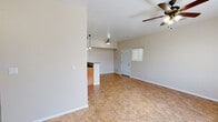 This single-story home offers a practical and functional layout designed for comfortable everyday living. The open-concept main area seamlessly connects the living room and kitchen, creating a spacious, airy feel. The living room features tile-style flooring, a ceiling fan with integrated lighting, and a large window fitted with blinds that allows natural light to fill the space. An entry door with an adjacent window provides a welcoming entryway. The kitchen is well-appointed with warm wood cabinetry, granite-style countertops, a black appliance suite including a freestanding electric range and refrigerator, an under-cabinet range hood, and a peninsula with pendant lighting overhead — ideal for casual dining or meal prep. The bedrooms are carpeted for added comfort, each benefiting from natural light through blinds-covered windows. At least one bedroom includes a sliding closet with built-in shelving. The full bathroom is neatly appointed with tile-style flooring, a wood vanity with a granite-style countertop, and a full tub-shower combination. Throughout the home, neutral wall tones and clean white trim provide a bright, move-in-ready atmosphere that serves as a versatile canvas for personalization.