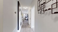 This well-appointed single-floor residence offers a cohesive, modern aesthetic throughout its thoughtfully laid-out living spaces. A welcoming entryway corridor, finished with light wood-look flooring and clean white trim, leads into the heart of the home, setting a polished tone from the moment you arrive.

The open living and dining area is bright and airy, featuring crown molding, wood-look flooring, and large French doors that flood the space with natural light and open to a private balcony. Bold, oversized wall art and a ceiling fan add character to the room.

The galley-style kitchen is efficiently designed with white cabinetry, dark granite countertops, a stainless steel sink, and stainless appliances. A convenient in-unit washer and dryer are tucked just beyond, adding everyday practicality.

The primary bedroom is a striking retreat, anchored by a dramatic navy blue textured accent wall with pendant lighting and plush carpet flooring. A second bedroom offers a softer, neutral palette with dual mirrors, warm lighting, and generous natural light from large windows.

Both bathrooms are finished with dark granite vanity counters and tiled flooring. One features a tub-shower combination, while the other includes a spacious vanity with ample storage. Together, these spaces form a stylish and functional home.