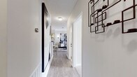 This well-appointed single-floor residence offers a cohesive, modern aesthetic throughout its thoughtfully laid-out living spaces. A welcoming entryway corridor, finished with light wood-look flooring and clean white trim, leads into the heart of the home, setting a polished tone from the moment you arrive.

The open living and dining area is bright and airy, featuring crown molding, wood-look flooring, and large French doors that flood the space with natural light and open to a private balcony. Bold, oversized wall art and a ceiling fan add character to the room.

The galley-style kitchen is efficiently designed with white cabinetry, dark granite countertops, a stainless steel sink, and stainless appliances. A convenient in-unit washer and dryer are tucked just beyond, adding everyday practicality.

The primary bedroom is a striking retreat, anchored by a dramatic navy blue textured accent wall with pendant lighting and plush carpet flooring. A second bedroom offers a softer, neutral palette with dual mirrors, warm lighting, and generous natural light from large windows.

Both bathrooms are finished with dark granite vanity counters and tiled flooring. One features a tub-shower combination, while the other includes a spacious vanity with ample storage. Together, these spaces form a stylish and functional home.