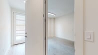 This contemporary multi-floor space is thoughtfully designed with a clean, modern aesthetic carried consistently throughout all four levels. The ground level includes a spacious garage with polished concrete flooring and integrated lighting, alongside an additional utility room with the same concrete finish, accessible through a secure entry door.

The main living level features an expansive open-plan layout with light hardwood flooring that flows seamlessly from the living area into the kitchen. The kitchen is a standout feature, equipped with white flat-panel cabinetry, a stone-speckled quartz island with an integrated sink, a marble-style tile backsplash, stainless steel appliances including a range, microwave, and refrigerator, and pendant lighting overhead. Natural light enters through a clerestory window above.

Upper floors continue the light hardwood flooring and white wall palette, with generously sized rooms featuring vaulted ceilings and large windows fitted with horizontal blinds. The primary bathroom offers a dual-sink vanity with quartz countertops, light wood cabinetry with gold hardware, large framed mirrors, and a marble-tiled walk-in shower, completing the refined, minimalist character of the space.