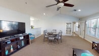 This single-floor facility offers a thoughtfully designed layout that balances comfort, functionality, and a welcoming atmosphere throughout. Visitors are greeted by a bright reception area with soaring ceilings, large windows that invite natural light, and coastal-inspired décor accented by teal and turquoise tones. A "Welcome" station near the entrance features a beverage station and informational displays, setting a warm, hospitable tone.

The open common area serves as the heart of the space, featuring vaulted ceilings with a ceiling fan, carpeted flooring, and a round dining table with ample seating. A standout tiled fireplace with a warm accent wall adds character to the lounge area, which also includes a large flat-screen TV and comfortable seating. French doors lead to an exterior area, allowing natural light to flow through.

A well-appointed kitchen features stainless steel appliances, white cabinetry, a granite-topped peninsula, and tile flooring. An adjacent hallway corridor with tile flooring connects key areas and includes a vending machine for added convenience.

The dedicated fitness room is well-equipped with free weights, resistance bands, stability balls, weight machines, and mirrors, offering a comprehensive workout space. Throughout, the space maintains a cohesive, cheerful aesthetic with bright artwork and clean, light-toned walls.