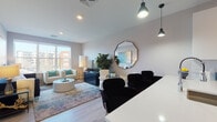 Located at 9 Tower Ln in New Haven, CT, this contemporary single-floor residence offers a well-designed open-concept layout that seamlessly connects the kitchen, dining, and living areas. The kitchen is a standout feature, equipped with stainless steel appliances including a gas range, microwave, refrigerator, and dishwasher. Dark lower cabinetry contrasts sharply with crisp white upper cabinets and a bright quartz peninsula countertop with bar seating, illuminated by sleek pendant lighting. Light wood-tone flooring flows throughout the main living area, contributing to an airy, modern aesthetic. The living room benefits from large windows that invite abundant natural light and offer views of the surrounding New Haven streetscape. A private bedroom features plush carpeting, a large window with city views, and ample space for furnishings. A hallway connects the bedroom to a clean, tiled bathroom complete with a walk-in shower framed by classic white subway tile. Neutral wall tones, recessed lighting, and contemporary finishes are consistent throughout, creating a cohesive and polished interior. The overall ambiance is modern, bright, and functional, making this residence a refined urban living option in the heart of New Haven.