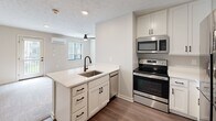 Located at 2701 Fletcher Ave in Lincoln, Nebraska, this efficiently designed studio offers a thoughtful layout that maximizes every square foot across a single floor. The open-concept living, dining, and kitchen area serves as the heart of the space, seamlessly blending functionality with modern style. The kitchen stands out with crisp white shaker cabinetry, light quartz countertops, a peninsula with an undermount sink and matte black faucet, and a full suite of stainless steel appliances including an electric range, over-the-range microwave, dishwasher, and a French door refrigerator. Wood-look flooring anchors the kitchen and entry areas, while the living space transitions to plush carpeting for added comfort. Natural light filters in through multiple windows fitted with blinds, and a ceiling fan overhead aids with air circulation. A wall-mounted mini-split system provides efficient climate control throughout. The living area also features direct access to an outdoor space via a glass-panel door. Recessed lighting and a textured ceiling complete the interior aesthetic. A bathroom and dedicated closet round out this well-appointed, move-in-ready space.