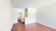 Located at 475 E Foothill Blvd in Pomona, California, this efficient single-floor unit offers a thoughtfully arranged layout comprising a living room, kitchen, bathroom, and closet. Warm, rich hardwood-style flooring runs throughout the main living areas, creating a cohesive and inviting atmosphere. The living room is bright and open, featuring a large window fitted with vertical blinds that allows generous natural light to filter in, along with views of the surrounding outdoor area, including a glimpse of a pool. A textured ceiling and clean white walls give the space a simple, neutral aesthetic. The kitchen is functionally appointed with a gas range, overhead microwave, and a window overlooking greenery, making it a practical cooking space. The bathroom is well-maintained and features a tiled tub-shower combination enclosed by sliding glass doors, a white vanity with sink, and a frosted window for natural light and privacy. A dedicated closet provides convenient storage. The unit's straightforward, clean design and consistent flooring throughout make it a practical and comfortable space suited for efficient everyday living in the heart of Pomona.
