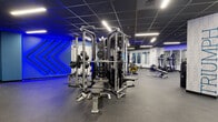 Located at 99 Pratt St in Hartford, CT, this contemporary fitness center spans a single floor and is thoughtfully organized into multiple dedicated workout zones. The facility features a striking design aesthetic throughout, with deep blue accent lighting, bold motivational typography on the walls — including phrases like "Achieve," "Discipline," "Excel," and "Success" — and dark drop-tile ceilings with sleek linear LED lighting that creates a dynamic, energizing atmosphere.

The strength training area is well-equipped with multi-station cable machines, weight stacks, and free-weight benches, all set on durable rubber flooring. A dedicated free weights room offers a full dumbbell rack, an adjustable bench, and wall-to-wall mirrors. The cardio zone houses treadmills, stair climbers, rowing machines, and stationary bikes, with interior windows along one wall that visually connect the spaces and enhance the sense of openness. A separate cycling studio accommodates spin bikes alongside wall mirrors, making it suitable for group or individual sessions.

Additional amenities include water fountains conveniently located near restroom entrances. The facility's cohesive, modern design and comprehensive equipment selection make it a well-rounded fitness destination for users of all training levels.